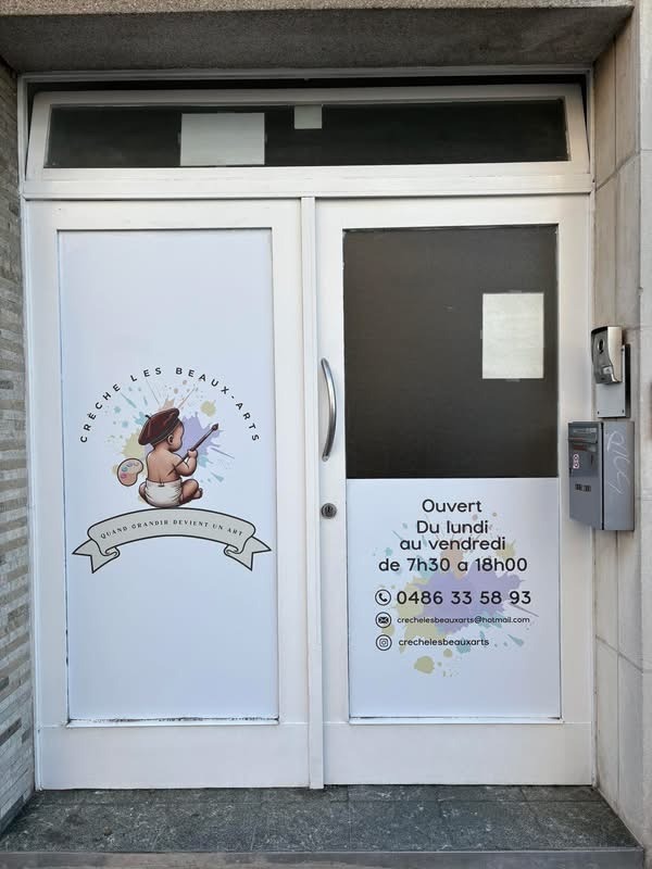 Porte d'entrée de la crèche Les Beaux-Arts, avec le logo de la crèche, ses horaires et ses coordonnées
